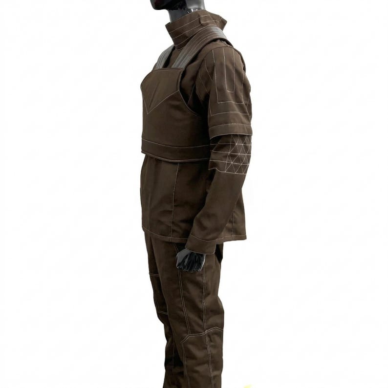 May include: A brown costume with a high collar, shoulder pads, and a chest piece. The sleeves have geometric white stitching. The trousers and jacket are brown with white stitching. The costume is displayed on a mannequin.