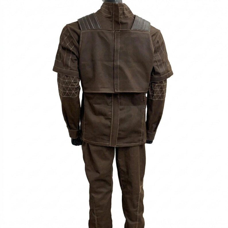 May include: A brown costume with a high collar, shoulder pads, and geometric stitching on the sleeves. The outfit includes a jacket and matching trousers. The costume is displayed on a mannequin.