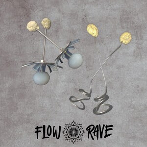 May include: Two pairs of flow props featuring metal rods, light blue spherical weights, and beige textured wicks. One pair has flat metal discs, while the other has coiled wire bases. The text "FLOW RAVE" with a spiral icon is centred below.