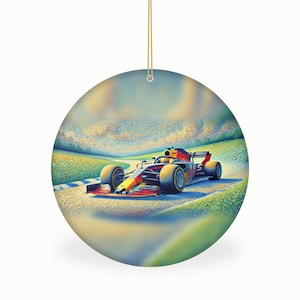 May include: A round ceramic ornament featuring a pointillist-style illustration of a Formula One race car in red, blue, and yellow on a track. The artwork uses small dots of color to depict the vehicle and surrounding landscape, suspended by a gold cord.