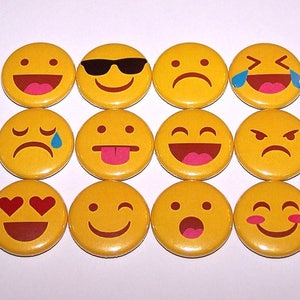 May include: A set of 12 yellow round button pins with different emoji faces. The emojis include a smiling face with sunglasses, a sad face, a laughing face with tears, a face with a tongue sticking out, a winking face, a surprised face, a heart-eyed face, a frowning face, a crying face, a laughing face, an angry face, and a blushing face.