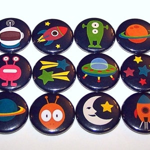 May include: A set of twelve circular pin-back buttons featuring space-themed graphics on a dark blue background. The designs include an astronaut helmet, rockets, planets, stars, a crescent moon, a flying saucer, and two different colorful alien characters.