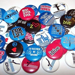 May include: A collection of colorful round buttons with various diving-themed designs and slogans. The buttons feature phrases like "Live Dive", "Eat Sleep Dive", "Best Diver Ever", and "Chlorine Junkie".