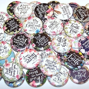 May include: A collection of circular pin-back buttons featuring various floral patterns and inspirational religious quotes in black script lettering. Each button displays unique text such as 'Be Strong and Courageous' or 'Trust in the Lord'.