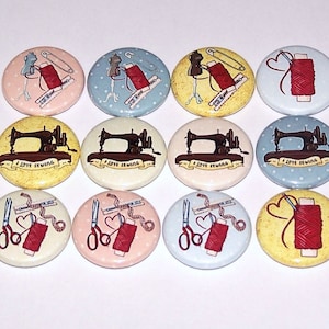 May include: Twelve round sewing themed buttons with various designs.  The designs include a sewing machine, spools of thread, scissors, and a pincushion.  The buttons are in various colors, including yellow, blue, pink, and white.
