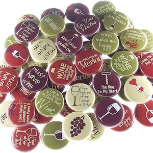May include: A collection of wine-themed buttons in various colors, including red, green, and cream. Each button features wine-related phrases and graphics, such as wine glasses, corkscrews, and grape clusters. The text includes phrases like "Wine Must Have" and "Keep Calm and Drink On."