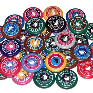 May include: A collection of colorful round buttons with various coffee-themed sayings. The buttons feature illustrations of coffee cups and mugs, with text such as "Coffee Makes Me Awesome", "Keep Calm and Drink Coffee", and "Life is One Cup at a Time".