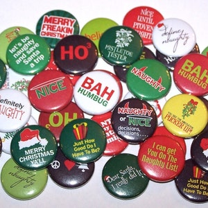 May include: A collection of 25 round Christmas themed buttons with various sayings, including "Naughty or Nice", "Bah Humbug", "You'll Shoot Your Eye Out!" and "Santa's Helper".