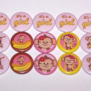 May include: Twelve pink, brown, and yellow round buttons with the text "it's a girl" and images of monkeys with bananas.