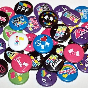May include: A collection of colorful round buttons with various designs and text related to color guard. The designs include peace signs, hearts, stars, flags, and the words "color guard", "live for", "guard", "rocks", "love", "spin", and "cutie".