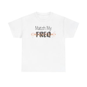 Pode incluir: Camiseta branca com a frase "Match My FREQ" em preto e um design de onda colorida. Uma peça casual para uso diário.