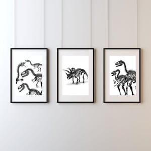 May include: Three framed black and white dinosaur skeleton art prints. The prints feature detailed illustrations of various dinosaur skeletons, including a Triceratops and other prehistoric creatures. The frames are black and the background is white.