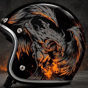 May include: A glossy black open-face motorcycle helmet featuring a detailed graphic of a phoenix in shades of grey and vibrant orange flames. The helmet includes a silver-toned metallic trim along the edge and three silver snap buttons on the side.