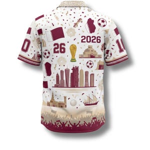 Peut inclure: Chemise blanche &agrave; boutons avec un motif r&eacute;p&eacute;t&eacute; de drapeaux bordeaux, de ballons de football et d'&eacute;l&eacute;ments architecturaux. Les chiffres "0" et "10" sont sur les manches. Le chiffre "26" et l'ann&eacute;e "2026" sont &eacute;galement visibles.