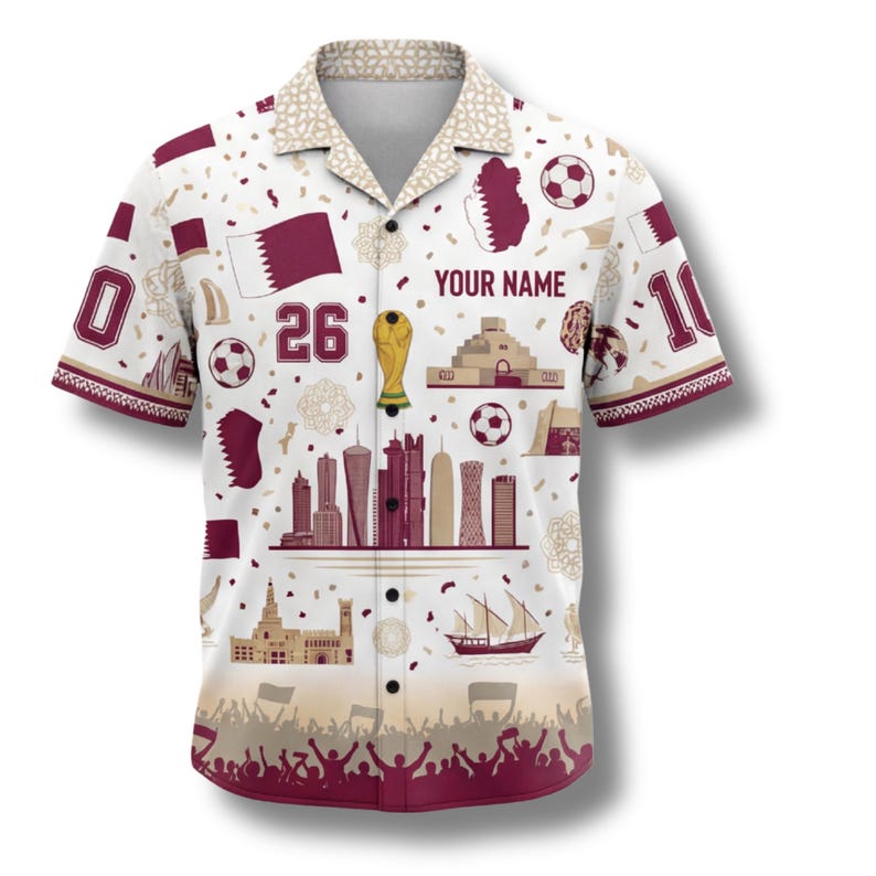 Peut inclure: Chemise blanche &agrave; motifs bordeaux et beige. La chemise pr&eacute;sente un ballon de football, le drapeau du Qatar et le texte "YOUR NAME". La chemise porte les num&eacute;ros 0, 10 et 26. La chemise a un col et des manches courtes.