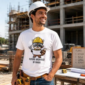 May include: White t-shirt with a cartoon raccoon wearing a hard hat and safety glasses, holding a wrench and a blank sign. The text "FUTURE ARCHITECT OF CHAOS" is below the raccoon. The person in the image is wearing a white hard hat and blue jeans.