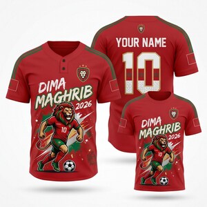 Op de afbeelding: Rood voetbalshirt met groene accenten, met een leeuwengrafiek en de tekst "Dima Maghrib 2026". De achterkant van het shirt toont het nummer 10 en ruimte voor een naam. Een kleinere versie van het shirt is ook zichtbaar.