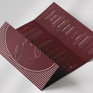 May include: A burgundy wedding program with white text and a semi-circular design. The program lists the wedding party, including the maid of honour, best man, bridesmaids, groomsmen, flower girl, and ring bearer.