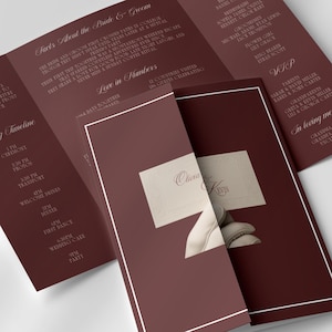 May include: A maroon wedding invitation suite, featuring a trifold brochure and an invitation card. The brochure displays wedding details, including the wedding party, timeline, and transportation information. The invitation card has the names "Clara & Kenny".