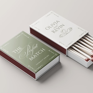 Op de afbeelding: Twee lucifersdozen, waarvan één open, met een bruiloftthema. De gesloten doos is saliegroen met de woorden "The Perfect Match" en de datum. De open doos is wit met de namen "Olivia en Kevin" en een zwanenontwerp. De lucifers hebben bruine koppen.