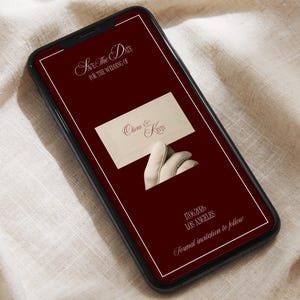 May include: A smartphone displays a burgundy wedding invitation design. The text reads "Save The Date" and "For the Wedding of" at the top. The invitation includes the names "Olivia & Kevin", the date, and location.