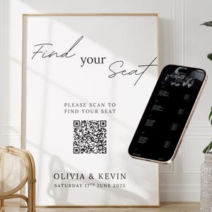 以下が含まれることがあります： 「Find your Seat」の文字とQRコードが記載された白いウェディング席次表。Olivia & Kevinの名前と日付も表示されています。スマートフォンには座席配置が表示されています。背景には装飾用の植物と椅子があります。