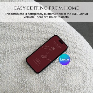 May include: A smartphone displays a burgundy wedding invitation design with the names "Emma & Oliver" in elegant script. The phone rests on a textured, off-white surface. The Canva logo is visible.