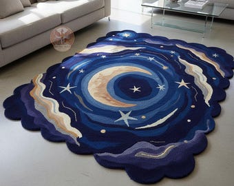 May include: A large, irregularly shaped rug with a celestial design. The rug features a crescent moon, stars, and swirling patterns in shades of blue, beige, and white. The rug's edges have a scalloped border.