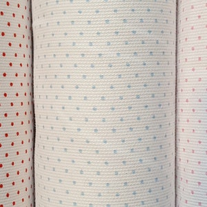 Op de afbeelding: Drie stofstalen met een witte achtergrond en verschillende gekleurde stippen. De stalen zijn rood, blauw en roze.