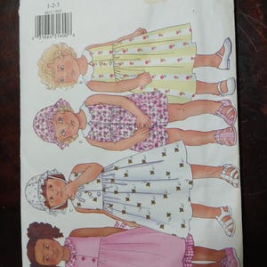 May include: Butterick sewing pattern 6611 featuring illustrations of little girls in dresses. The dresses are in various colors and patterns, including yellow with floral prints, pink with floral prints, white with bee prints, and a solid pink dress.