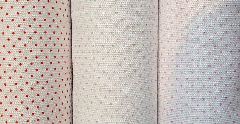 Op de afbeelding: Drie stofstalen met een witte achtergrond en verschillende gekleurde stippen. De stalen zijn rood, blauw en roze.