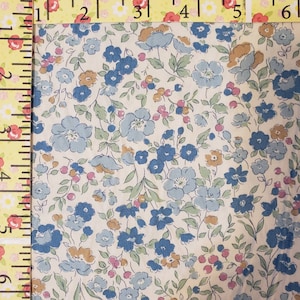May include: A white fabric with a blue and brown floral pattern. The fabric is covered in small flowers and leaves.