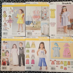 May include: Six sewing pattern packages for children's clothing. The patterns are from Simplicity and include designs for dresses, shirts, pants, and skirts. The patterns feature a variety of colors and styles, including floral prints, plaid, and solid colors.