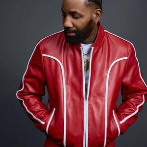 May include: A red leather jacket and matching pants set with white trim. The jacket has a zipper closure and pockets. The outfit is a bold, stylish statement.