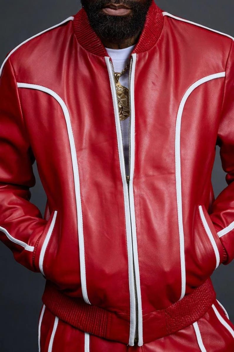 May include: A red leather bomber jacket with white trim accents. The jacket features a zipper closure, pockets, and a ribbed collar and cuffs. The jacket is part of a matching set.