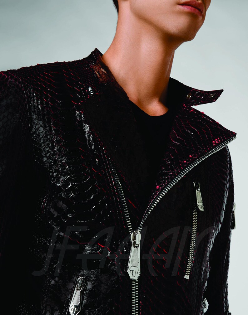 May include: A black and red leather jacket with a snakeskin pattern. The jacket has a silver zip and two silver zipped pockets. The collar is a classic biker style.