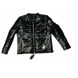 May include: Black leather jacket featuring a skeleton rib cage design on the front. The jacket has a full-length gold zipper, two zippered pockets, and a small tag attached. The sleeves are long, and the jacket is laid flat.