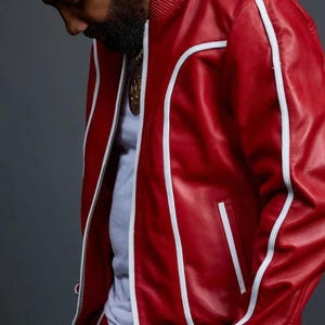 May include: Red leather jacket with white trim and a matching red track suit. The jacket has a zipper closure and a ribbed collar. The outfit is a bold, stylish statement.