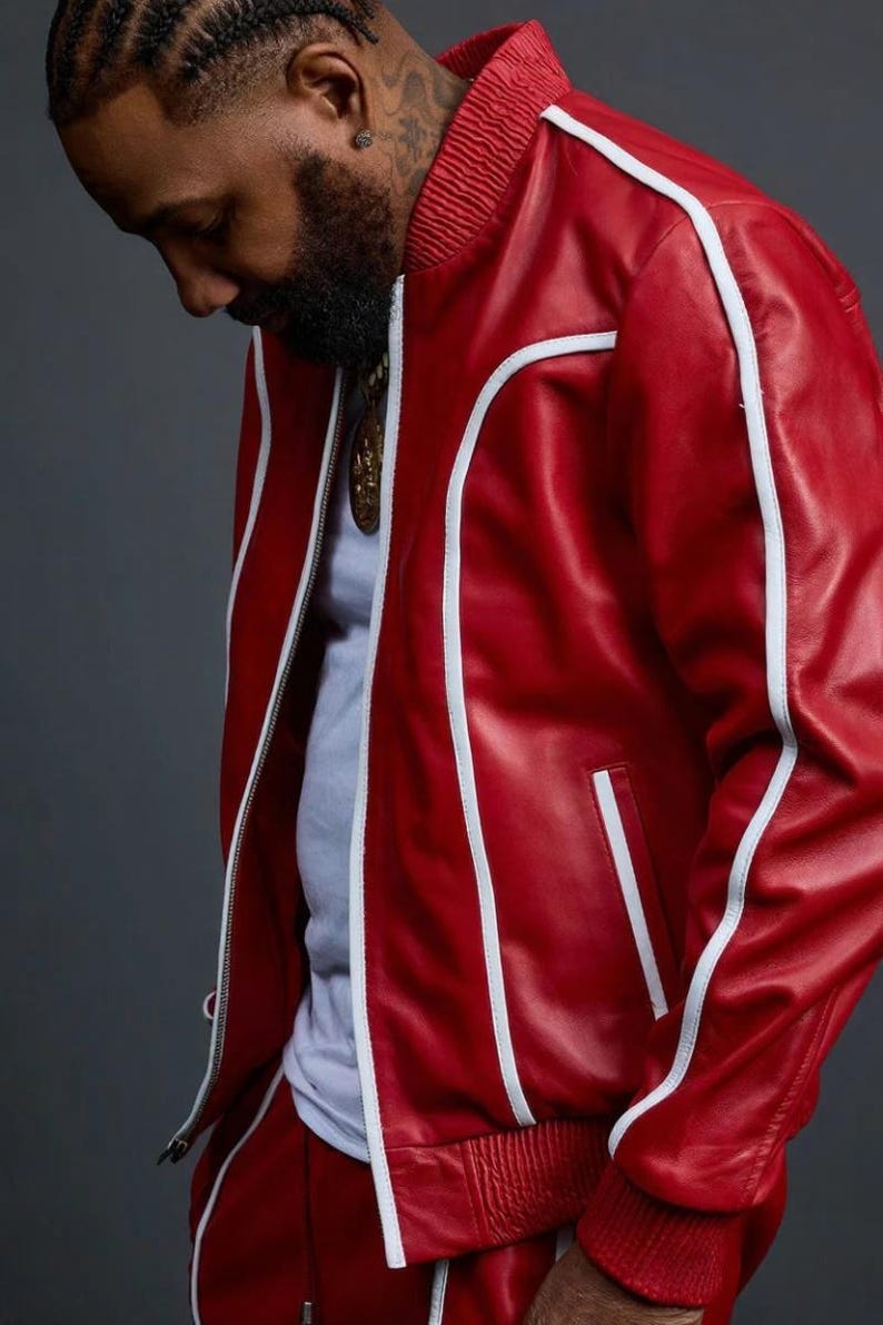 May include: Red leather jacket with white trim and a matching red track suit. The jacket has a zipper closure and a ribbed collar. The outfit is a bold, stylish statement.