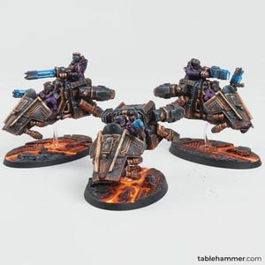 May include: Three miniature sci-fi vehicles with riders. The vehicles are primarily dark gray and bronze with blue energy weapons. The riders wear purple and gray uniforms. The bases are oval-shaped with a lava-like design.