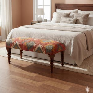 May include: A decorative bench with a patterned fabric seat in shades of red, orange, yellow, and gray. The bench has four dark wooden legs and is placed at the foot of a bed with neutral-colored bedding. The room has a warm, inviting atmosphere.