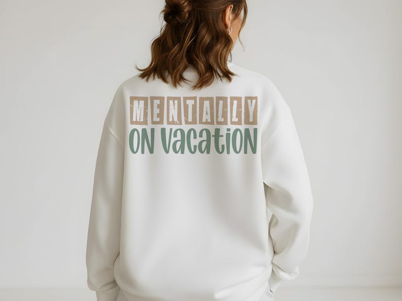 Back of white sweatshirt featuring beige and green mentally on vacation text.