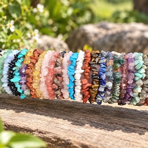 May include: A collection of multiple stretch bracelets made from various polished gemstone chips. The bracelets feature a wide array of colors including black, light green, blue, turquoise, yellow, pink, white, red, brown, purple, and orange.
