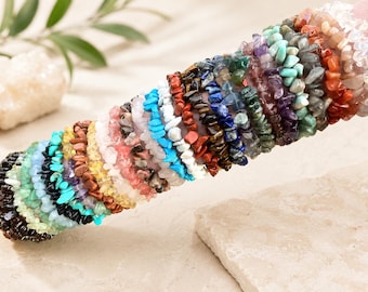 Könnte beinhalten: Eine Sammlung mehrerer elastischer Armbänder aus kleinen, unregelmäßig geformten, getrommelten Edelstein-Splittern in einer Vielzahl von Farben, darunter Schwarz, Türkis, Gelb, Rosa, Violett, Blau, Grün und Orange, angeordnet in einer langen Reihe.