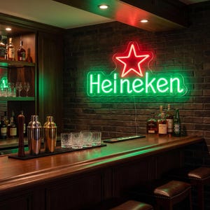 May include: A neon sign with the Heineken logo, featuring a red star and green lettering, hangs on a brick wall above a wooden bar. The bar is stocked with glassware, cocktail shakers, and bottles of liquor.