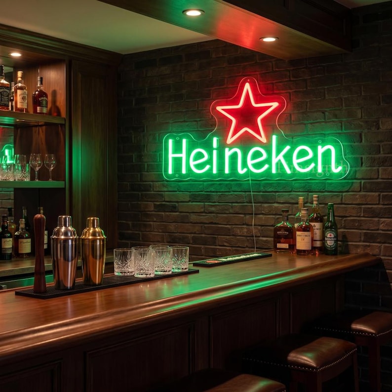 May include: A neon sign with the Heineken logo, featuring a red star and green lettering, hangs on a brick wall above a wooden bar. The bar is stocked with glassware, cocktail shakers, and bottles of liquor.