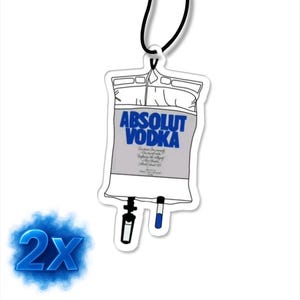 Könnte beinhalten: Ein weißer Lufterfrischer in Form eines Infusionsbeutels mit dem blauen Schriftzug "Absolut Vodka". Er hat eine schwarze Schnur zum Aufhängen. Eine blaue "2X" Grafik befindet sich unten links.