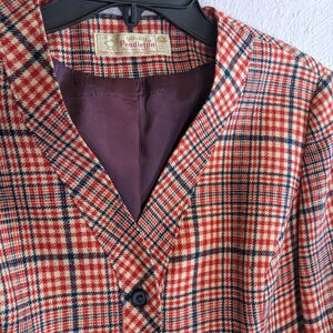 May include: A vintage Young Pendleton blazer in a red, cream, and navy plaid pattern. The blazer features a V-neck, a single button closure, and a dark purple lining. The Young Pendleton label is visible near the collar.