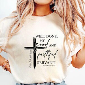 May include: A cream-coloured t-shirt with a black cross design. The text reads "WELL DONE, MY GOOD AND FAITHFUL SERVANT" and Matthew 25:21. The shirt also includes the text "charlie kirk 1993-2025".