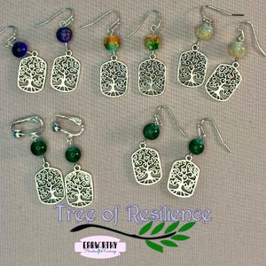 May include: A collection of handcrafted earrings with a tree of life design. The earrings feature silver-toned metal pendants and colorful beads in various shades of blue, green, and yellow. The text "Tree of Resilience" is visible.